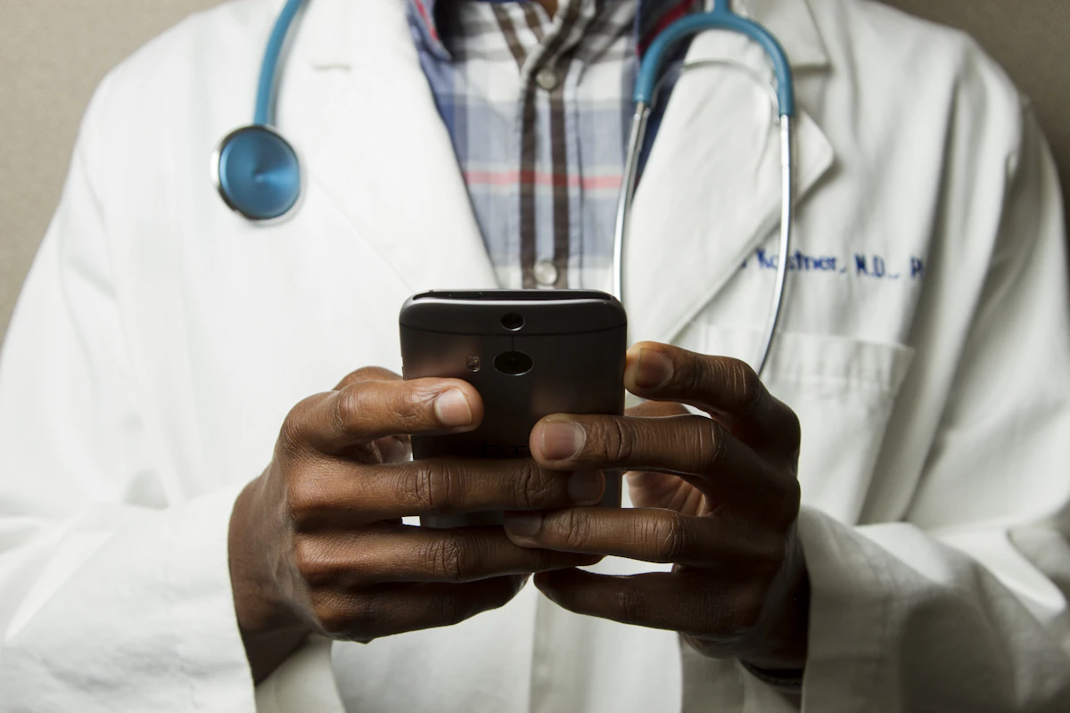 Läkare i vit rock som håller en mobiltelefon